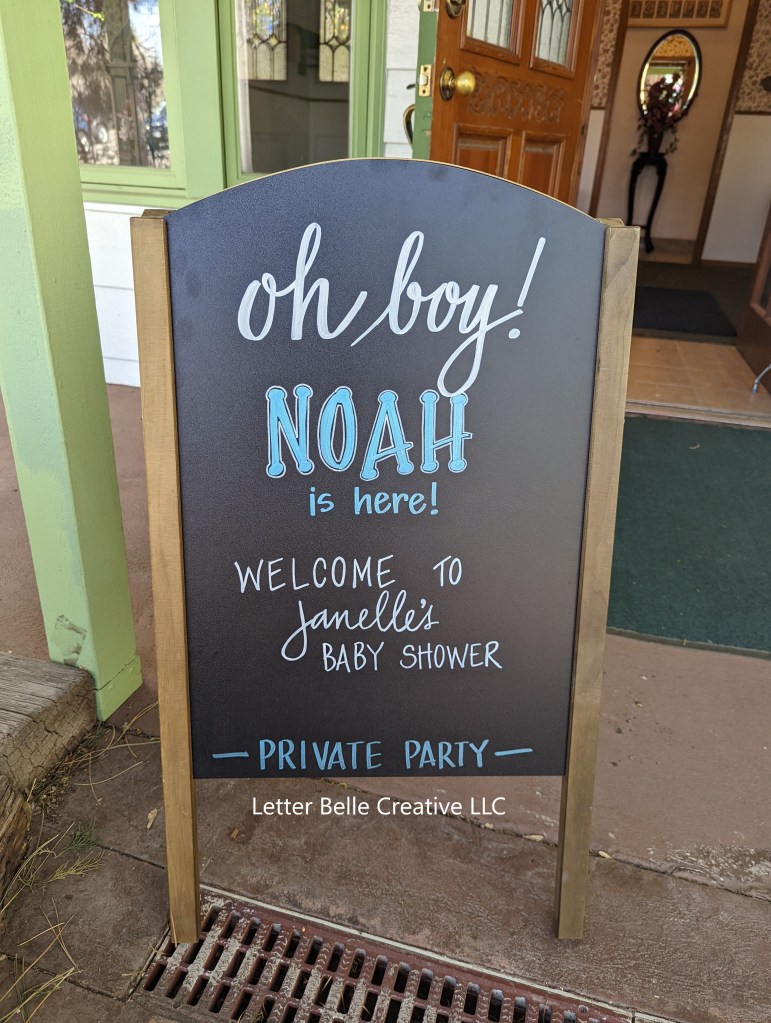 Black chalkboard with white & blue hand lettering. Oh boy! Noah is here! Welcome to Janelle's baby shower. -Private party-

Letter Belle Creative