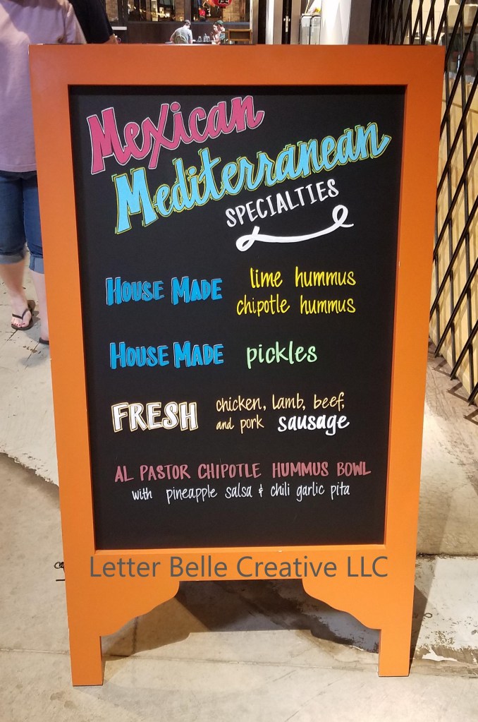 Orange framed chalkboard with hand lettering in bright colors for Elita Foods at Stanley Marketplace. Mexican Mediterranean specialties: house made lime hummus & chipotle hummus, house made pickles, fresh chicken, lamb, beef, and pork sausage. Al Pastor Chipotle Hummus Bowl

Letter Bell Creative