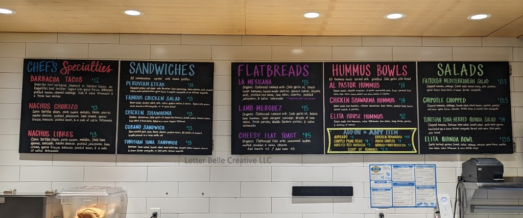 2 large rectangular chalkboards hanging on a white tiled wall. Colorful handwriting listing Chef's Specialties, Sandwiches, Flatbreads, Hummus Bowls, and Salads

Letter Belle Creative