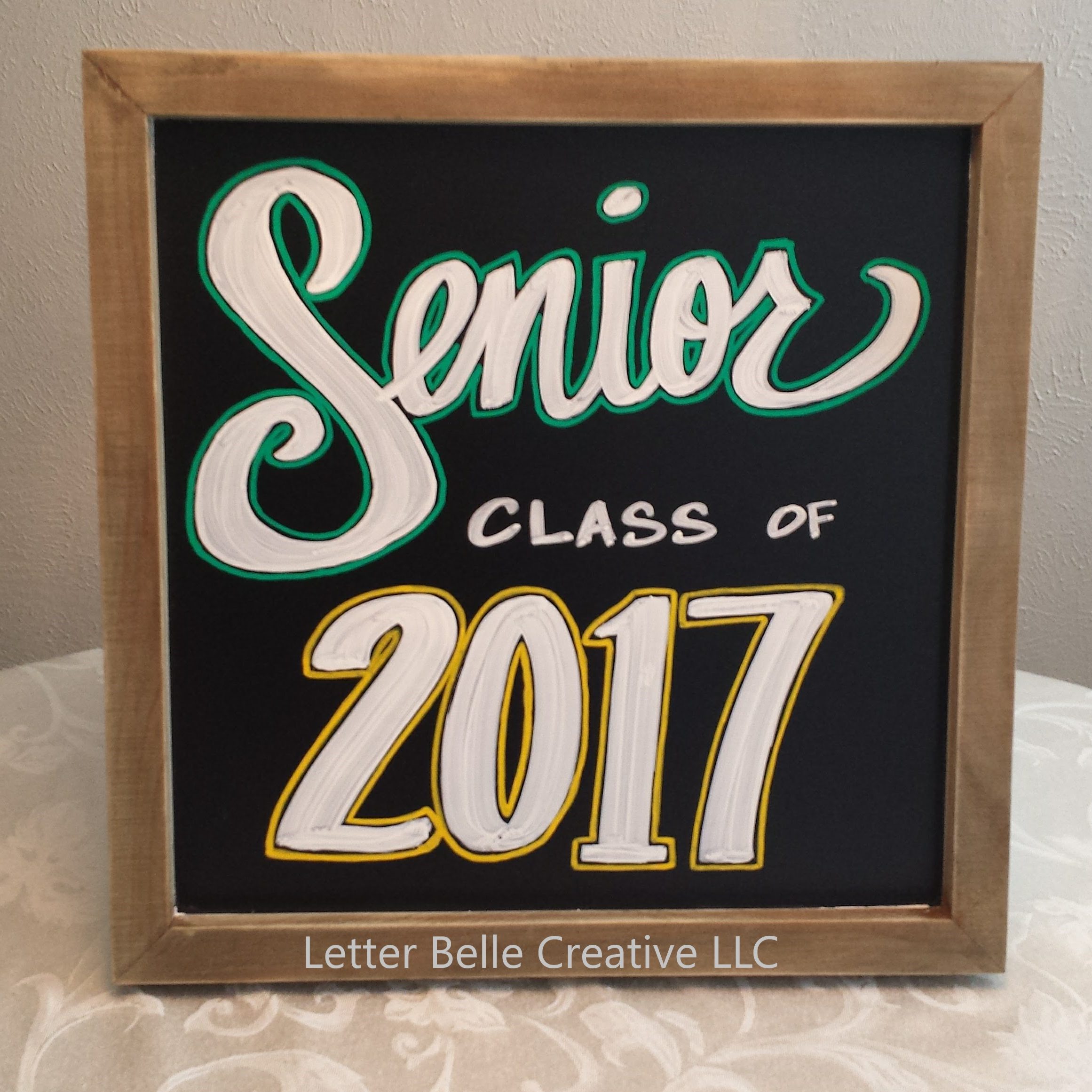 Square framed chalkboard with white letters with green & yellow outlines:  Senior. Class of 2017. Used as prop in Senior photos

Letter Belle Creative